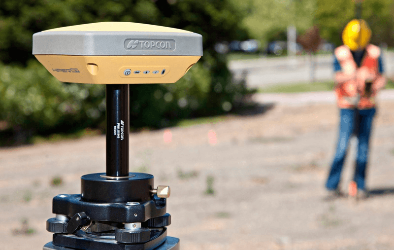 Kỹ sư cầm máy GNSS RTK Hi-Target tại một khu đất để đo đạc ranh giới